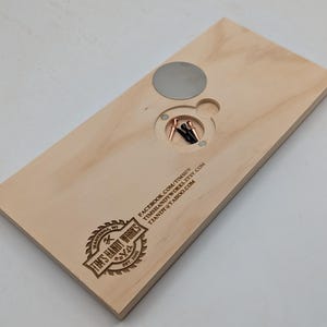 May include: A wooden board with a circular cutout and a metal disc. The board has a logo for "Tim's Handy Works" and contact information: "facebook.com/timshandyworks", "timshandyworks.etsy.com", and "timshandyworks@yahoo.com".