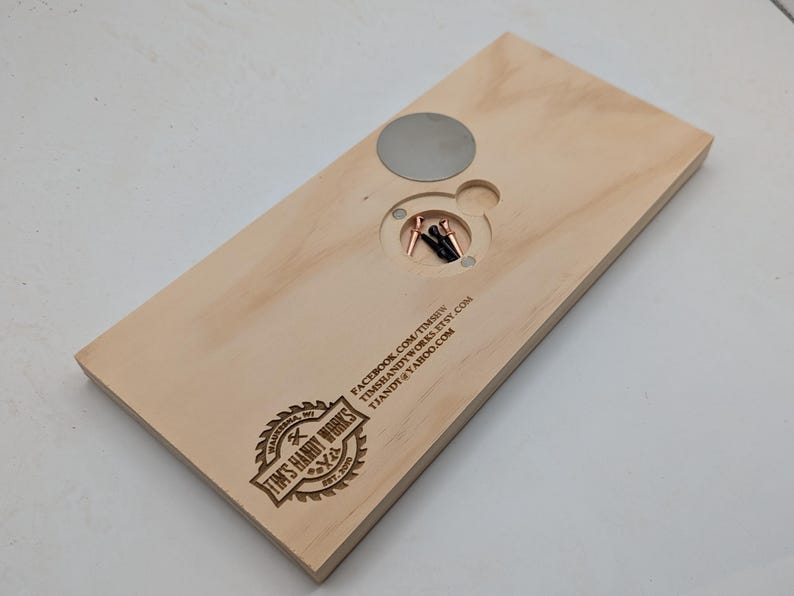 May include: A wooden board with a circular cutout and a metal disc. The board has a logo for "Tim's Handy Works" and contact information: "facebook.com/timshandyworks", "timshandyworks.etsy.com", and "timshandyworks@yahoo.com".