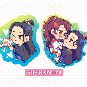 Peut inclure: Deux breloques en acrylique de style anime représentant des personnages aux longs cheveux noirs. L'une des breloques montre un personnage tenant un poisson rouge, tandis que l'autre montre deux personnages en interaction. Le texte "Acrylic Charms" est affiché sous les breloques.