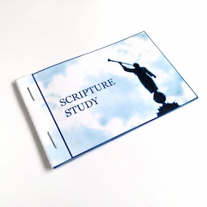May include: A blue and white booklet with the text "SCRIPTURE STUDY" on the front cover. The cover features a silhouette of an angel blowing a trumpet against a cloudy sky background.