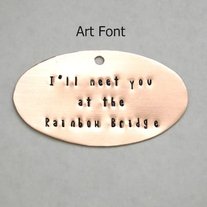 Puede incluir: Etiqueta ovalada de cobre con el texto "I'll meet you at the Rainbow Bridge" en una fuente manuscrita.