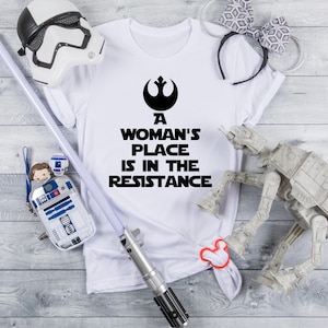 May include: White t-shirt with a black Rebel Alliance symbol and the text "A woman's place is in the resistance".