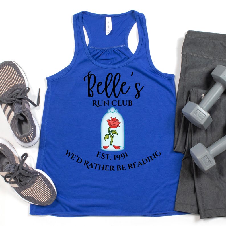 May include: A royal blue tank top with the text "Belle's Run Club" and a graphic of a rose in a glass dome. The text "We'd Rather Be Reading" and "Est. 1991" are also printed on the shirt. Gray athletic shoes, gray leggings, and dumbbells are also in the image.