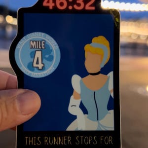 May include: A blue and black sticker with a picture of Cinderella and the text "Walt Disney World Marathon Mile 4" and "This runner stops for all mile markers". The sticker has a red digital timer that reads "46:32".