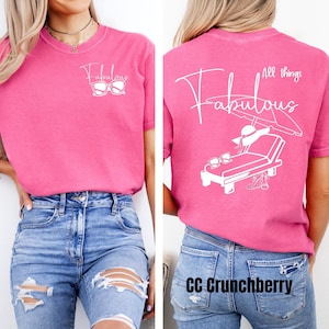 May include: Pink t-shirt with a white graphic design that says "Fabulous" with sunglasses on the front and "All things Fabulous" with a beach chair, umbrella, and sunglasses on the back.