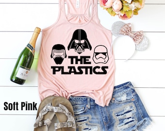 May include: A soft pink tank top with a black graphic of three Star Wars characters, Darth Vader, Kylo Ren, and a Stormtrooper, with the text "The Plastics".