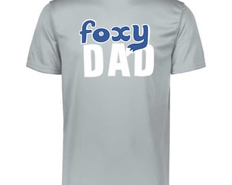 Peut inclure: T-shirt gris clair à manches courtes avec l'inscription "foxy DAD" imprimée sur le devant. Le mot "foxy" est en bleu et le mot "DAD" est en blanc. Le t-shirt a un col rond.