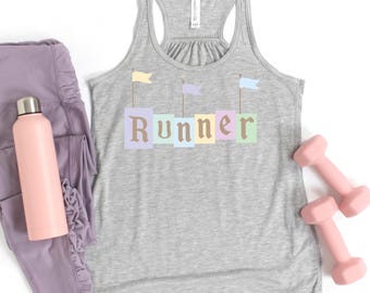 May include: A gray racerback tank top with the word "Runner" in pastel colors. The tank top has three small flags above the word. A pink water bottle, lavender leggings, and two pink dumbbells are also in the image.