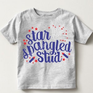 Puede incluir: Una camiseta gris con un dise&ntilde;o azul y rojo que dice "star spangled stud" con estrellas rojas y fuegos artificiales.