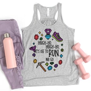 May include: A gray racerback tank top with the text "Heigh-Ho, It's off to Run We Go" surrounded by colorful gem and fitness-themed graphics. The image also includes a pink water bottle, purple leggings, and two pink dumbbells.