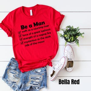 May include: Red t-shirt with a white checklist and the text "Be a Man" followed by a list of qualities: "swift as a coursing river", "force of a great typhoon", "strength of a raging fire", "mysterious as the dark side of the moon".