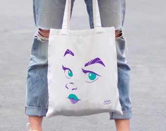 May include: A white tote bag featuring a cartoon face illustration in purple and teal. The face has a surprised expression with large eyes and a slightly open mouth.
