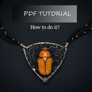 Puede incluir: Un collar con un colgante triangular que presenta un diseño de escarabajo negro y dorado. El colgante está rodeado por una malla de alambre plateado. El collar está hecho de cuentas negras con detalles dorados. El texto "PDF TUTORIAL How to do it?" se muestra sobre el colgante.