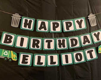 May include: A festive birthday banner with the words "HAPPY BIRTHDAY ELLIOT" in black letters on white squares with green scalloped edges. The banner includes recycling symbols, trash cans, and garbage truck cutouts.