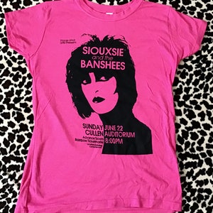 May include: Pink t-shirt with a black and white image of Siouxsie and the Banshees. The text "Pace and SPB Present" is at the top of the shirt. The text "SUNDAY JUNE 22 CULLEN AUDITORIUM 8:00PM" is at the bottom of the shirt.