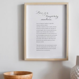 May include: A black and white printable art print with a quote about love being a temporary madness. The quote is written in a cursive font and is framed in a light wood frame.
