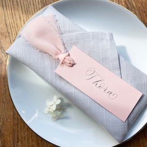 Elegant blush calligraphy wedding place names with frayed ribbon