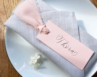 Elegant blush calligraphy wedding place names with frayed ribbon