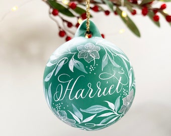 Hand painted personalised ceramic bauble in winter green and silver with botanical illustration
