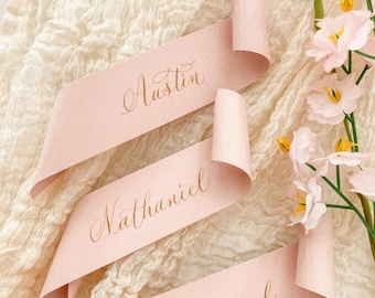 Blush pink scroll wedding place cards on recycled paper