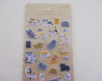 May include: A sheet of decorative stickers featuring various cat designs in shades of gray, yellow, white, and black. The stickers are arranged on a beige, scalloped-edge backing with Japanese text.