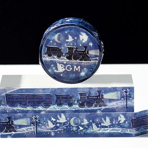 May include: A blue and white washi tape with a design of a train traveling through a starry night sky. The tape features a crescent moon, stars, and birds flying in the sky. The text "BGM" is printed on the tape.