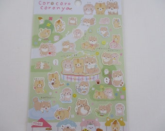 May include: A sheet of stickers featuring cartoon Shiba Inu dogs in various poses. The stickers are in shades of tan, brown, and white, with some accented by pink and green. The sheet has the text "Corocoro coronya" at the top.