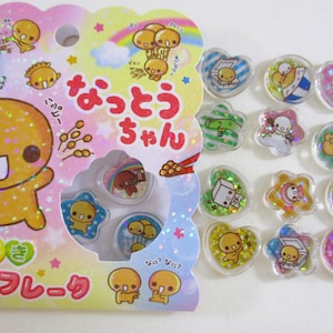 May include: A sheet of colorful, glittery stickers featuring a cartoon character named "Natsutsu-chan". The stickers are shaped like hearts, stars, and flowers. The stickers are packaged in a clear plastic sheet with a colorful background.