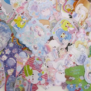 May include: A collection of colorful, whimsical stickers with various designs. The stickers feature cartoon characters, musical notes, ice cream, and other cute illustrations. Pastel colors like pink, blue, and purple dominate the designs, creating a playful and charming aesthetic.
