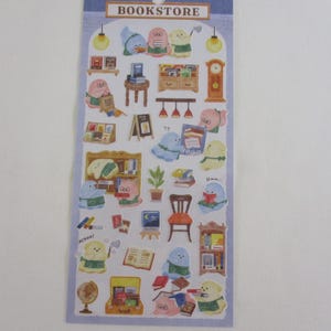 May include: A sticker sheet with a bookstore theme. The stickers feature cartoon characters reading books, bookshelves, clocks, and other bookstore-related items. The sheet has a light blue border with the word "BOOKSTORE" at the top.