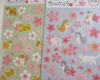 May include: Two sheets of stickers featuring adorable illustrations of Shiba Inu dogs and cats with cherry blossoms. The stickers are on a light green and light blue background. The text on the stickers reads "さくらどまり" and "さくらんぼり".