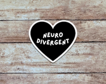 May include: A black heart-shaped sticker with a white border featuring the text NEURO DIVERGENT in white capital letters. The sticker is centered and displays a clean, bold font against the solid black background of the heart shape.