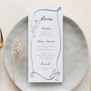 May include: A white rectangular menu card with blue cursive text and line art of a seashell, starfish, and wine glasses. The menu lists Starter, Main Course, and Desert. It is placed on a light grey plate with a gold fork and knife on the sides.
