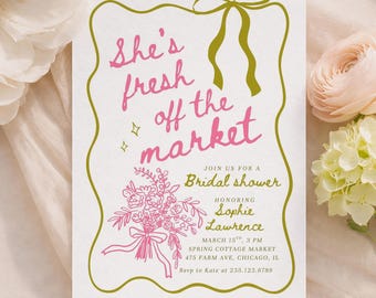 May include: A white rectangular bridal shower invitation card featuring a green scalloped border with a bow at the top. The text reads: She's fresh off the market, Join us for a Bridal shower, Honoring Sophie Lawrence, March 15th, 3 PM, Spring Cottage Market, 475 Farm Ave, Chicago, IL, Rsvp to Kate at 235.123.6789. A pink floral illustration is at the bottom left.