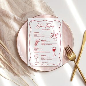 May include: A wine tasting scorecard with red line art illustrations of a wine bottle, grapes, and wine glasses. The scorecard is on a pink plate with gold cutlery and dried plants.