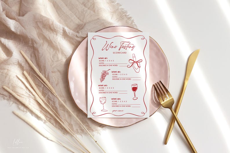 May include: A wine tasting scorecard with red line art illustrations of a wine bottle, grapes, and wine glasses. The scorecard is on a pink plate with gold cutlery and dried plants.