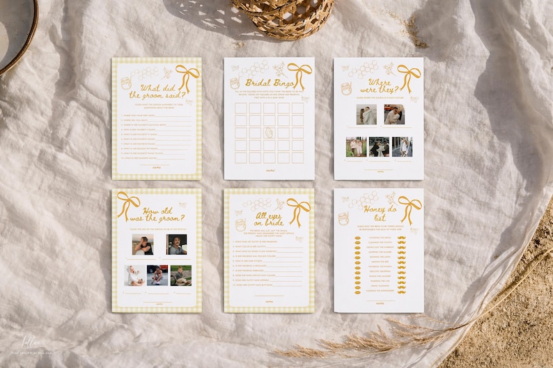 K&ouml;nnte beinhalten: Sechs Hochzeitsspielkarten mit gelb-wei&szlig;em Vichy-Rand und goldenem Text. Die Spiele umfassen "Was hat der Br&auml;utigam gesagt?", "Hochzeitsbingo" und "Honey do list". Die Karten sind auf einer wei&szlig;en Oberfl&auml;che angeordnet.
