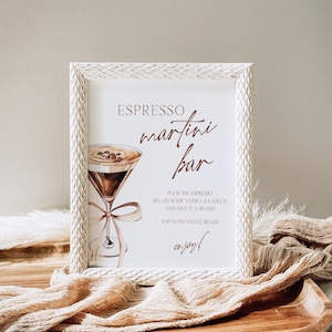 May include: White framed sign with the text "ESPRESSO martini bar" in brown lettering.  The sign also includes a watercolor illustration of a martini glass with coffee beans and a ribbon.  The text below the illustration reads "POUR THE ESPRESSO SPLASH SOME VODKA & KAHLUA AND GIVE IT A SHAKE TOP WITH COFFEE BEANS enjoy!"