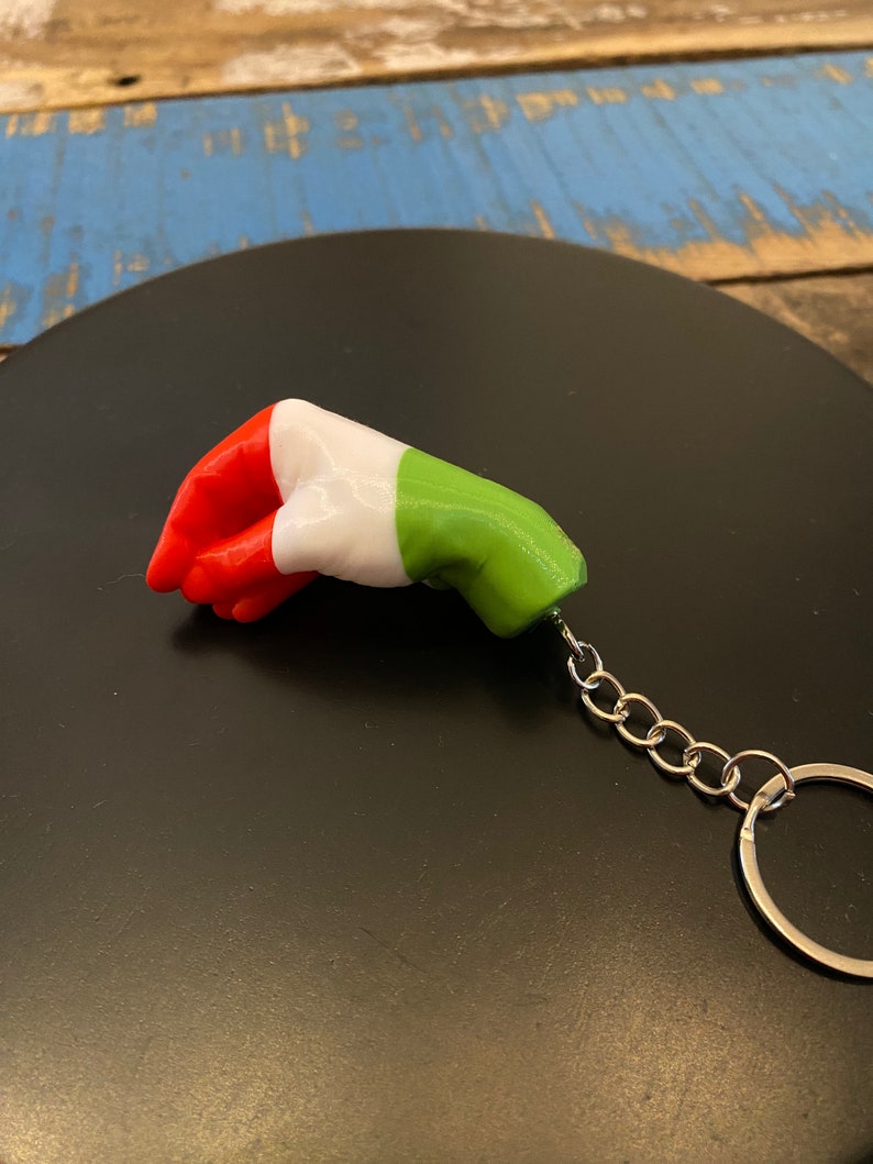 Peut inclure: Un porte-cl&eacute;s en forme de drapeau italien, vert, blanc et rouge. Le drapeau est attach&eacute; &agrave; une cha&icirc;ne et un anneau argent&eacute;s.