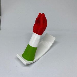 K&ouml;nnte beinhalten: Eine 3D-gedruckte Handskulptur, die in den Farben der italienischen Flagge bemalt ist. Die Hand macht eine Geste mit ausgestreckten Fingern und eingezogenem Daumen. Die Skulptur ist auf einem wei&szlig;en Sockel montiert.