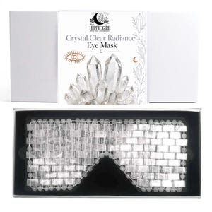 May include: A clear crystal eye mask composed of rectangular stone segments strung together, presented in a black-lined white box. The packaging features the text "This Hippie Girl" and "Crystal Clear Radiance Eye Mask" with a crystal cluster graphic.