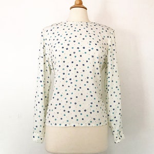 May include: A white long-sleeved blouse with a blue and green floral print.