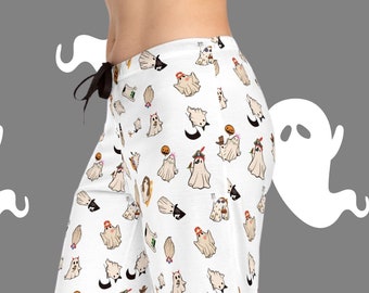 Puede incluir: Pantalón de pijama blanco con un estampado de temática de Halloween que presenta fantasmas vestidos con varios disfraces. El estampado incluye una variedad de colores y patrones.