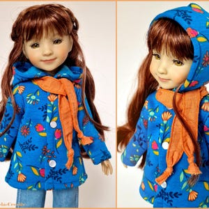 Könnte beinhalten: Eine Puppe in einer blauen Jacke mit Blumenmuster und einem orangefarbenen Schal. Die Jacke hat eine Kapuze und weiße Knöpfe. Die Puppe hat lange braune Haare und trägt eine blaue Jeans.