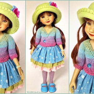 May include: A doll wearing a green hat with a pink flower, a knitted sweater in shades of blue, purple, and pink, and a blue skirt with white floral patterns. The doll has red hair and is wearing blue shoes.