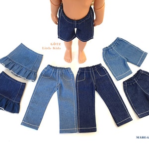 Puede incluir: Varias prendas de vestir de muñecas de mezclilla, incluyendo pantalones cortos, faldas y pantalones, se muestran sobre una superficie blanca. Las prendas son en tonos azules y presentan costuras blancas. La imagen incluye el texto "Götz Little Kidz" y "MABE-la-Creativ".