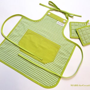 Könnte beinhalten: Grün-weiß kariertes Schürzen mit einer großen grünen Tasche und einem Namensschild mit der Aufschrift "Elias". Die Schürze wird mit zwei passenden grün-weiß karierten Topflappen geliefert.