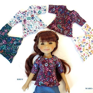 Könnte beinhalten: Fünf Blusen für Puppen mit floralem Muster in verschiedenen Farben, darunter Weiß, Türkis, Burgunderrot und Rosa. Die Blusen haben kurze Ärmel und einen runden Ausschnitt. Eine Puppe trägt eine burgunderrote Bluse mit floralem Muster.
