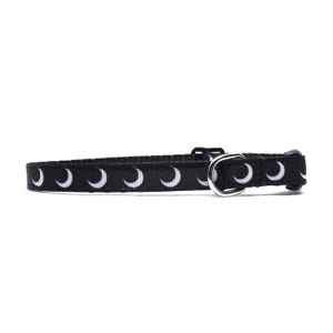 May include: Black cat collar with a white crescent moon pattern.
