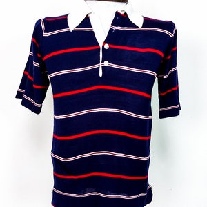 May include: A navy blue short-sleeved polo shirt with red and white stripes. The shirt has a button-up collar and a three-button placket.